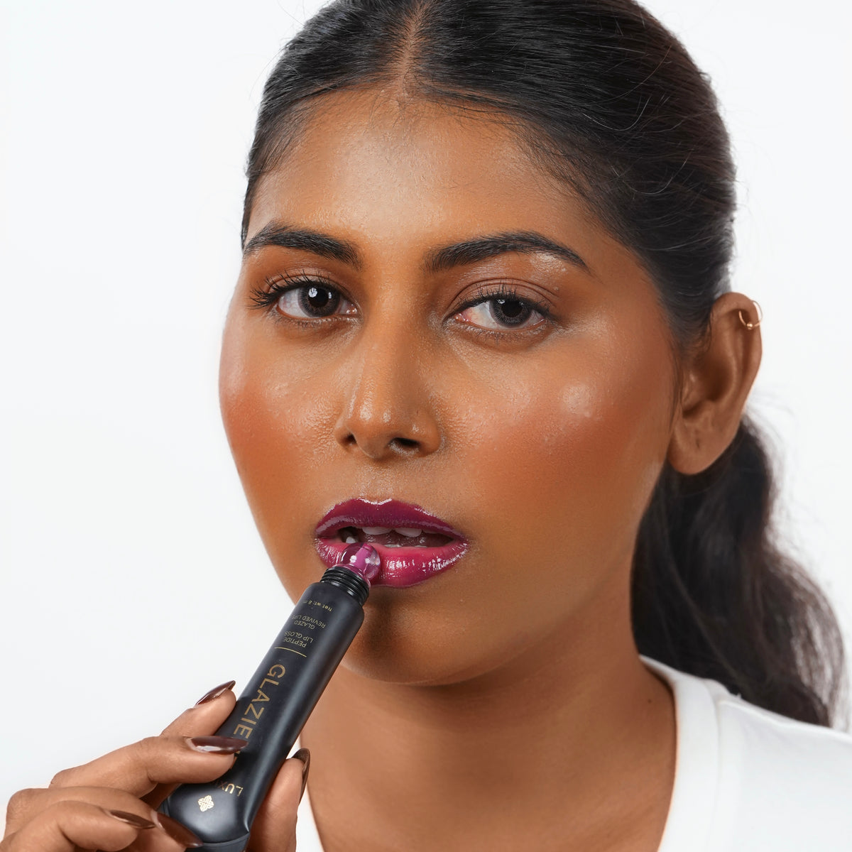 Rose_Pink Indian woman with dark skin applying purple lip gloss
