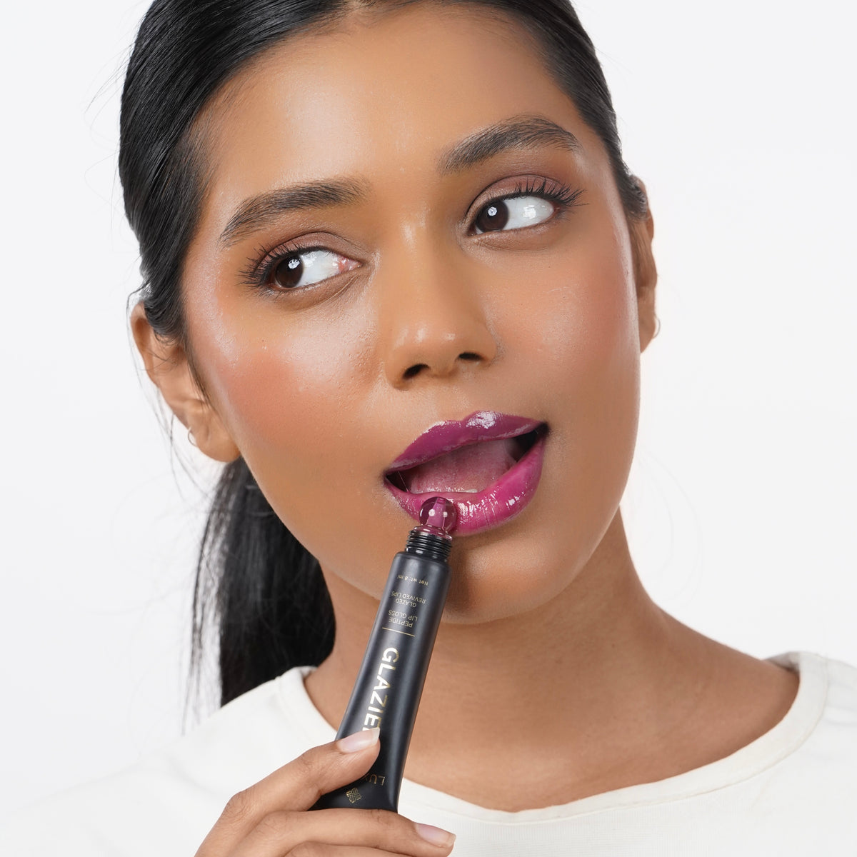Rose_Pink Indian woman with medium skin applying purple lip gloss