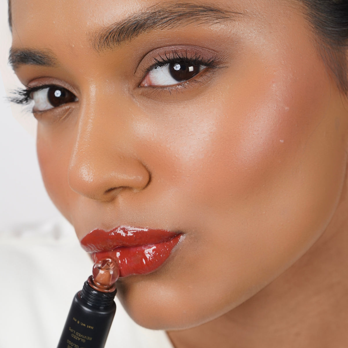 Toasted_Nude Indian woman with medium skin applying Glazient Toasted Nude nude lip gloss
