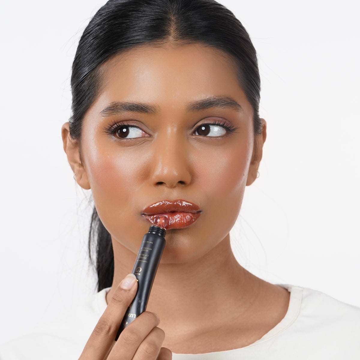 Warm_Caramel Indian woman with medium skin applying Glazient Warm Caramel nude lip gloss